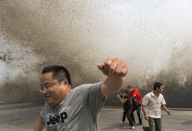 Visitors run away from a wave caused by a tidal bore which surged past a barrier on the banks of Qiantang River, in Hangzhou, Zhejiang province, China, August 30, 2015. (Photo by Reuters/China Daily)