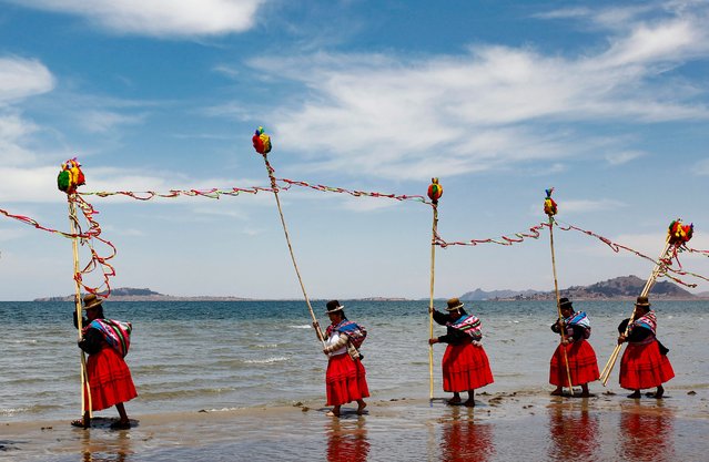 Aymara peasants dressed in typical ceremonial attire dance making offerings on the shore of Titicaca Lake, close to the village of Perka, Puno Province, Peru, on October 6, 2023, with the intention to please the spirits and bring an end to the drought that has caused an abnormal descent of the water level. Quechua, Aymara and other highland Andes etnias living by the lake are suffering from an extended draught season. The absence of rain has affected crop cicles and drinking water shortages (Photo by Juan Carlos Cisneros/AFP Photo)