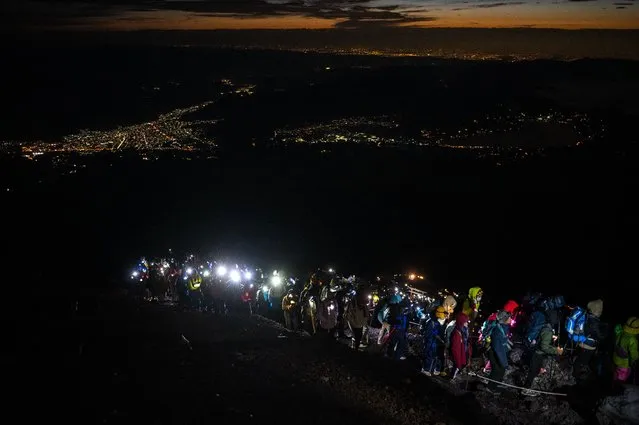 People climb to the summit of Mount Fuji early on August 15, 2022, some 70 kilometres (43 miles) west of the capital Tokyo. (Photo by Philip Fong/AFP Photo)