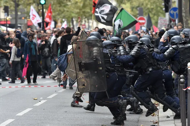 Antiriot police charge protesters on the sidelines of a demonstration on October 10, 2017 in Paris, part of a nationwide strikes and demonstrations day called by nine unions representing 5,4 million public sector workers to show their “profound disagreement” with French president's bid to transform the gargantuan public service and government's plans to freeze their pay and eliminate 120000 public jobs. The protests are the fourth round of demonstrations in France since September aimed at forcing the 39-year-old president to row back on his reforms, with the government's response being closely watched by European allies and investors. (Photo by Christophe Archambault/AFP Photo)