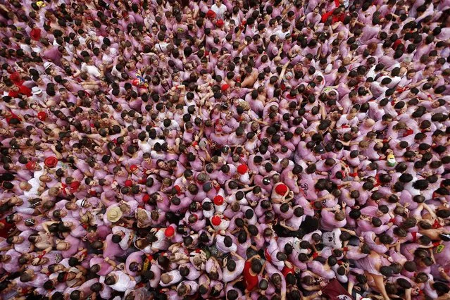 Revelers pack the town hall square during the launch of the “Chupinazo” rocket, to celebrate the official opening of the 2014 San Fermin fiestas, in Pamplona, Spain, Sunday, July 6, 2014. (Photo by Daniel Ochoa de Olza/AP Photo)