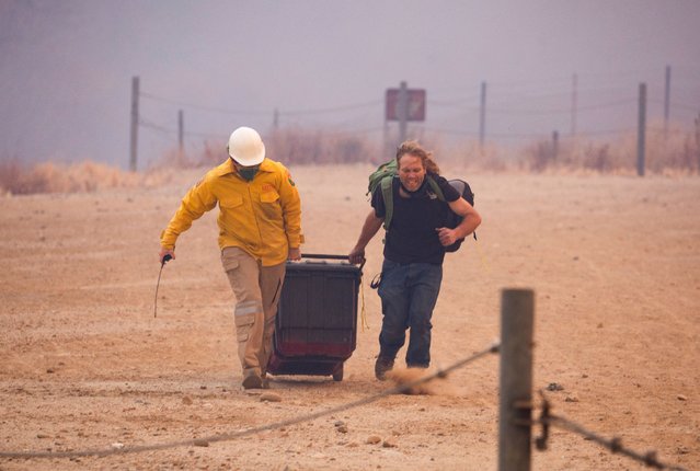 A member of the media helps a resident as firefighters and aircraft battle the Hughes Fire near Castaic Lake, north of Santa Clarita, California, U.S. January 22, 2025. (Photo by Ringo Chiu/Reuters)