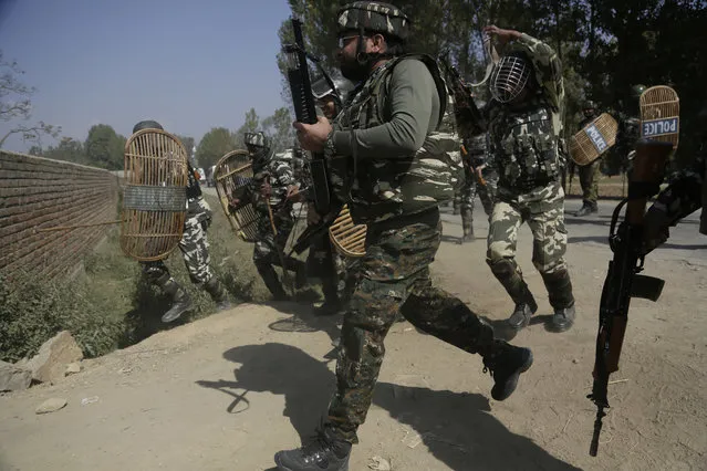 Security forces chase Kashmiri villagers who clashed with them in Hajin, 38 kilometers (24 miles) north of Srinagar, Indian controlled Kashmir, Wednesday, October 11, 2017. Soldiers began an anti-militant operation by cordoning off northern Hajin town on a tip that rebels were hiding in the area. Two Indian air force commandos and two rebels were killed in the ensuing intense fighting. Street clashes erupted shortly after the fighting ended as hundreds of residents demanded an end to Indian rule in Kashmir. (Photo by Mukhtar Khan/AP Photo)