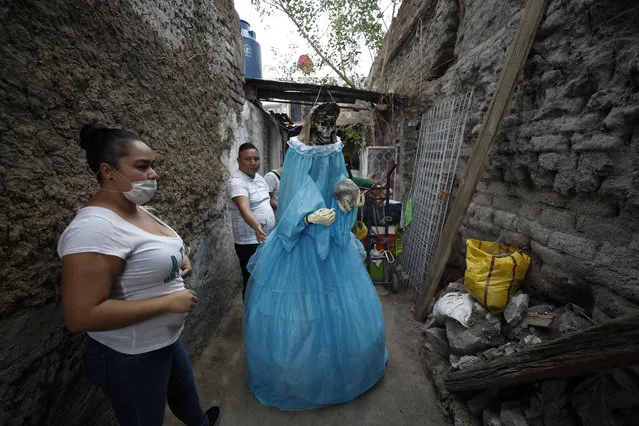 Neighbors help to return a giant figure of the “Santa Muerte”, or Death Saint, to a home, after it was displayed in the street to celebrate the saint's monthly festival day, which drew thousands of devotees despite the ongoing coronavirus pandemic, in Mexico City's Tepito neighborhood, Monday, June 1, 2020. Despite the ongoing coronavirus pandemic, thousands of devotees, few wearing face masks amidst the dense crowd, made the monthly pilgrimage Monday to pray or give thanks to Santa Muerte, one of several unofficial folk saints worshipped in Mexico. (Photo by Rebecca Blackwell/AP Photo)