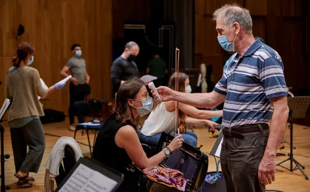 The conductor of the Cascais & Oeiras Chamber Orchestra, Maestro Nikolay Lalov, takes a member's body temperature during a rehearsal in the Auditório da Senhora da Boa Nova the day before their first performance before a live audience during the COVID-19 Coronavirus pandemic on June 05, 2020 in Cascais, Portugal. This concert will be the first in Portugal since the beginning of the pandemic and is being performed on June 6 for the occasion of Cascais Day, the 656th anniversary of the city, as the country is coming back to life with the third phase of the de-confinement that started on June 02. (Photo by Horacio Villalobos/Corbis via Getty Images)