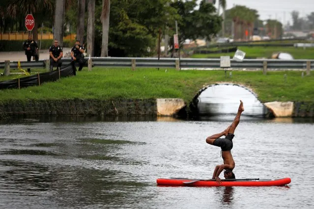 A man stands on his head on a paddle board as pollice officers look at him during a protest against racial inequality in the aftermath of the death in Minneapolis police custody of George Floyd, outside Trump National Doral golf resort in Doral, Florida, U.S., June 6, 2020. (Photo by Marco Bello/Reuters)