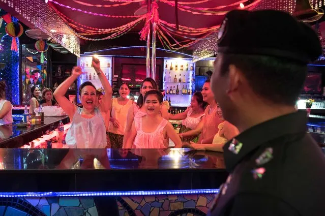 This photo taken on March 29, 2017 shows Thai Police Lieutenant Colonel Sulasak Kalokwilas (R) interacting with bartenders at an outside bar as he patrols Walking Street in Pattaya. (Photo by Roberto Schmidt/AFP Photo)