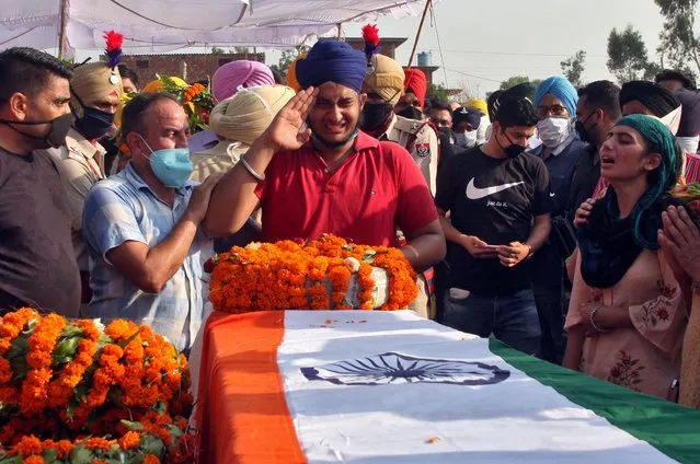 Prabhjot Singh, son of Satnam Singh, an Indian soldier who was killed in a border clash with Chinese troops in Ladakh region, reacts next to the coffin of his father during his funeral ceremony in Bhojraj village in Gurdaspur, Punjab on June 18, 2020. (Photo by Munish Sharma/Reuters)