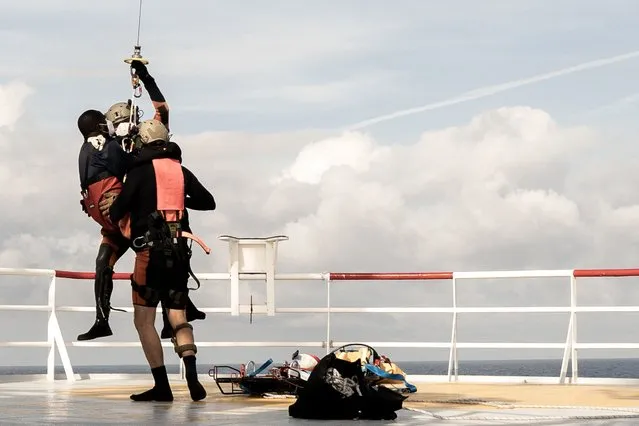A migrant in need of urgent medical care (C) is winched up by a helicopter of the French Army from the Ocean Viking rescue ship on November 10, 2022 in the Tyrrhenian Sea between Italy and Corsica island. French authorities said on November 10, 2022 they would evacuate three migrants from the Ocean Viking rescue ship in need of urgent medical care, plus one caregiver, amid a standoff between France and Italy over where the rest of the passengers should disembark. (Photo by Vincenzo Circosta/AFP Photo)