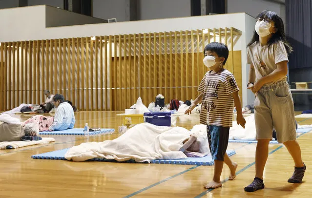 Children wearing face masks walk at a shelter after being evacuated, in Ashikita town, Kumamoto prefecture, southwestern Japan, Saturday, July 4, 2020. Heavy rain triggered flooding and mudslides on Saturday as more than 75,000 residents in the prefectures of Kumamoto and Kagoshima were asked to evacuate following pounding rains overnight. (Photo by Kyodo News via AP Photo)