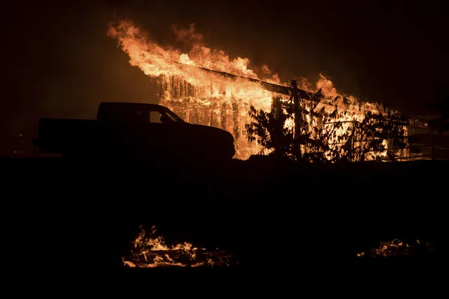 Flames consume a structure as a wildfire burns in Casitas Springs, Calif., on Tuesday, December 5, 2017. Wind-driven fires tore through California communities Tuesday for the second time in two months, leaving hundreds of homes feared lost and uprooting tens of thousands of people. (Photo by Noah Berger/AP Photo)