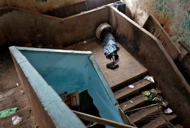 A porter sleeps on a stairway at a wholesale market in Bengaluru, India, November 30, 2017. (Photo by Abhishek N. Chinnappa/Reuters)