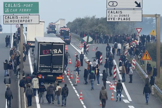 Dozens of migrants gather near lorries which head towards the ferry terminal in Calais, France, October 3, 2015. (Photo by Pascal Rossignol/Reuters)