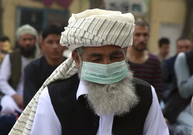 An Afghan Muslim man wearing a face mask as a precaution against coronavirus offers Eid al-Adha prayers in Kabul, Afghanistan, Friday, July 31, 2020. Muslims worldwide marked the the Eid al-Adha holiday over the past days amid a global pandemic that has impacted nearly every aspect of this year's celebrations. (Photo by Rahmat Gul/AP Photo)