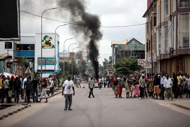 People look on as protesters burn tyres during a demonstration calling for the President of the Democratic Republic of the Congo (DRC)to step down on January 21, 2018 in Kinshasa. At least one person was killed in Kinshasa on January 21 after security forces opened fire to disperse protesters at a banned march demanding that the President stand down, the UN and witnesses said. (Photo by John Wessels/AFP Photo)
