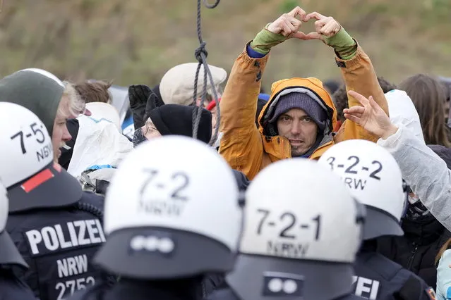 An activist forms a heart with his hands in the direction of the police officers near the village of Luetzerath, Germany, 10 January 2023. The village in the North Rhine-Westphalia state is to make way for lignite mining despite the decision to phase out coal. The Garzweiler open pit mine, operated by German energy supplier RWE, is in the focus of protests by people who want Germany to stop mining and burning coal as soon as possible in the fight against climate change. (Photo by Ronald Wittek/EPA/EFE)