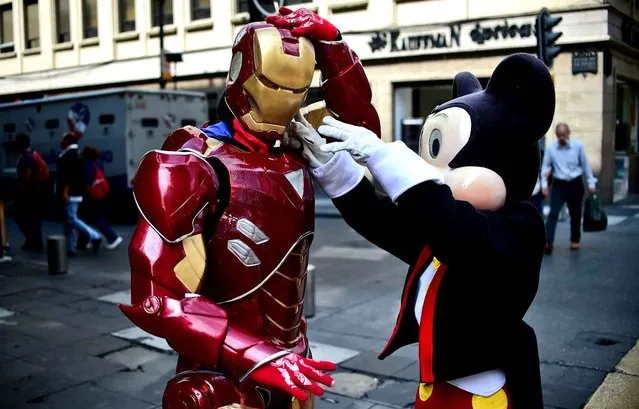 Two informal workers dressed up as Ironman and Mickey Mouse get ready to work in Mexico City, on September 22, 2016. The workers pose with local residents and tourists for pictures in the streets of the Mexican capital. (Photo by Ronaldo Schemidt/AFP Photo)