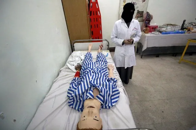 A nursing student stands by a medical mannequin inside Omar Bin Abd Alazeez Nursing institute in a rebel-controlled area of Aleppo, Syria October 25, 2015. (Photo by Hosam Katan/Reuters)
