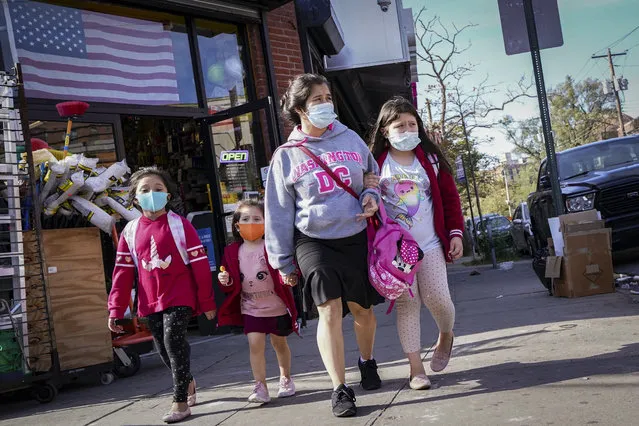 Pedestrians in masks pass a store on Thursday, October 15, 2020, as government restrictions on business activity limit operations due to an increase of COVID-19 cases, in the Far Rockaway neighborhood of the borough of Queens in New York. After shutdowns swept entire nations during the first surge of the coronavirus earlier this year, some countries and U.S. states are trying more targeted measures as cases rise again around the world. (Photo by John Minchillo/AP Photo)