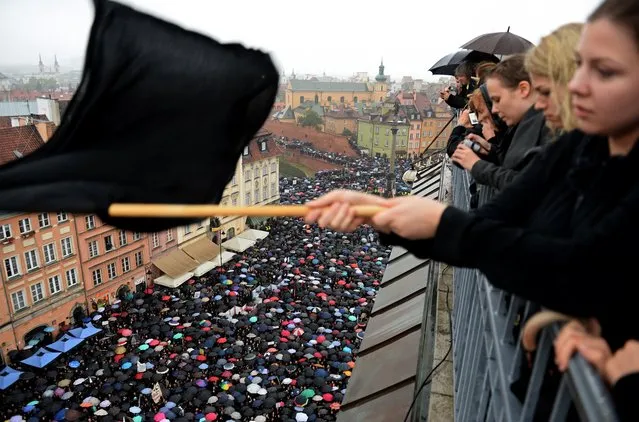 A girl waves a black flag as people take part in a nationwide strike and demonstration to protest against a legislative proposal for a total ban of abortion on October 3, 2016 in Warsaw. Thousands of women dressed in black protested across Poland in the “Women strike” campaign against a proposed near-total abortion ban in the devoutly Catholic country where legislation is already among the most restrictive in Europe. (Photo by Janek Skarzynski/AFP Photo)