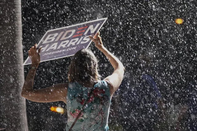 A supporter stands in the rain as Democratic presidential candidate former Vice President Joe Biden speaks at a drive-in rally at the Florida State Fairgrounds, Thursday, October 29, 2020, in Tampa, Fla. (Photo by Andrew Harnik/AP Photo)