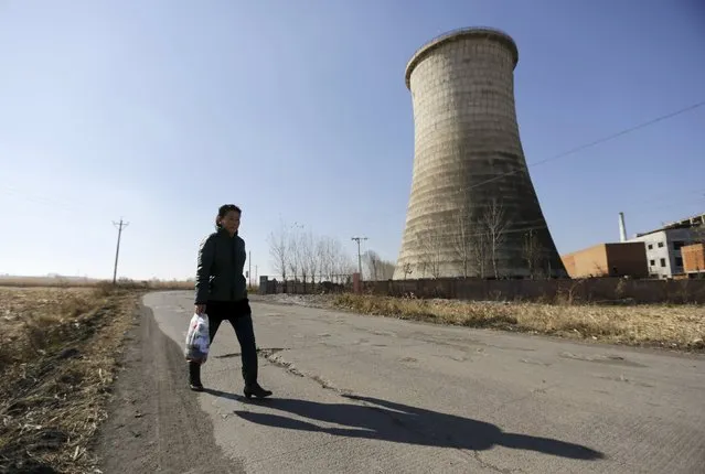 A woman walks past a cooling tower outside a state-owned coal mine on the outskirts of Jixi in Heilongjiang province, China, October 23, 2015. (Photo by Jason Lee/Reuters)
