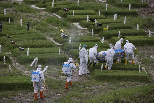 Workers in protective suits carry a coffin containing the body of someone who presumably died of the coronavirus for burial in Medan, North Sumatra, Indonesia, Tuesday, November 24, 2020. (Photo by Binsar Bakkara/AP Photo)