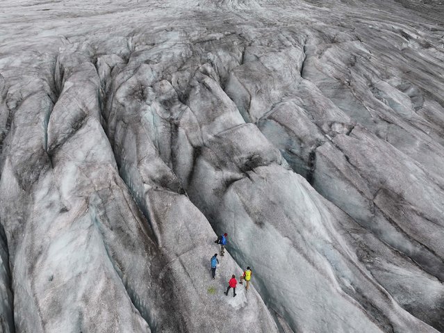 A scientific team from the Swiss Federal Institute of Technology in Zurich stands among crevasses on the Rhône Glacier while collecting data near Gletsch, Switzerland, on Friday, August 22, 2025. The Rhône Glacier, among Switzerland’s largest, is likely facing another withering year following record-breaking temperatures across Europe in June and overall low levels of snowfall. (Photo by Sean Gallup/Getty Images)