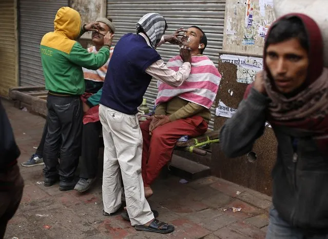 Men get their shave and moustache groomed by roadside barbers on a winter morning in the old quarters of Delhi December 19, 2014. (Photo by Ahmad Masood/Reuters)