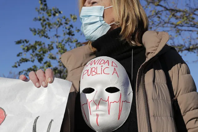 One of around 200 health professionals protest at the entrance of the Nurse Isabel Zendal Hospital as officials entered the state-of-the-art facility, built in 100 days at a cost of 100 million euros (119 dolllars), twice the original budget in Madrid, Spain, Tuesday, December 1, 2020. Authorities in Madrid held a ceremony to open part of a 1,000-bed hospital for emergencies that critics say is no more than a vanity project, a building with beds not ready to receive patients and unnecessary now that contagion and hospitalizations are waning. Spain has officially logged 1.6 million infections and over 45,000 deaths confirmed for COVID-19 since the beginning of the year. Message on mask reads “Public heath service”. (Photo by Paul White/AP Photo)