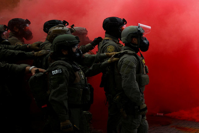 Law enforcement officers stand amid smoke from a smoke grenade released to disperse demonstrators in front of U.S. Immigration and Customs Enforcement (ICE) headquarters in Portland, Oregon, U.S., October 4, 2025. (Photo by Carlos Barria/Reuters)