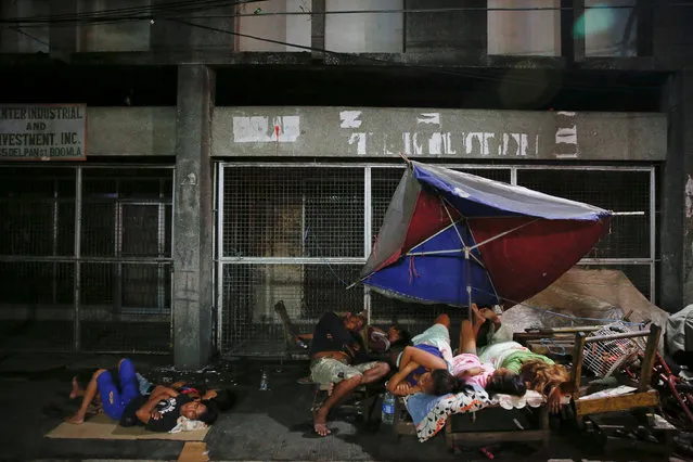 People sleep in open air, on a street in Tondo, Manila, Philippines early October 18, 2016. Local residents from the neighbourhood in Manila's slum of Tondo in which several people were killed in drugs related operations, say there are more people sleeping outside their homes since the beginning of the country's war on drugs fearing for their safety. (Photo by Damir Sagolj/Reuters)