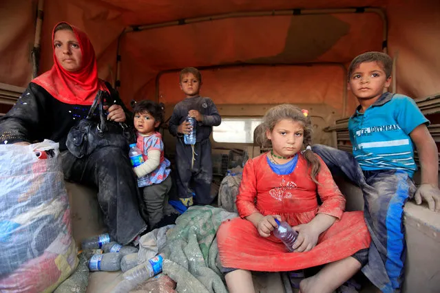 Displaced people who are fleeing from clashes sit at a military vehicle in Qayyarah, during an operation to attack Islamic State militants in Mosul, Iraq, October 19, 2016. (Photo by Alaa Al-Marjani/Reuters)