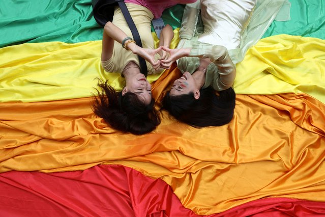 Silvia, 30, and Arui, 18, from China lay on a rainbow flag at the annual LGBTQ+ Pride parade in Bangkok, Thailand on June 1, 2024. (Photo by Chalinee Thirasupa/Reuters)