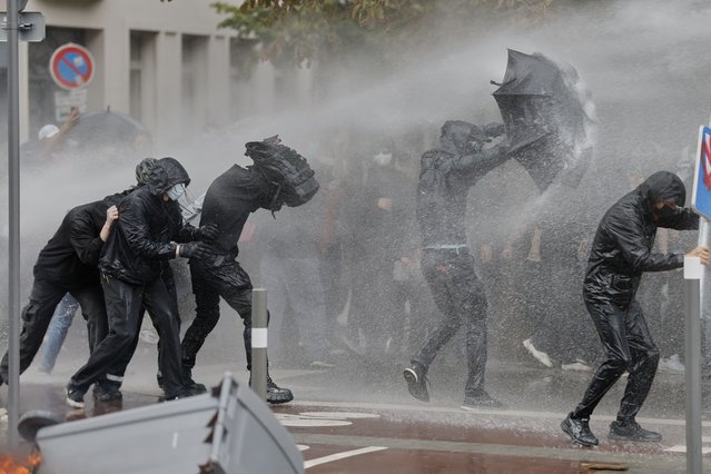 Protesters of the “Block Everything” movement take cover from a spraying water canon in Lille, northern France, Wednesday, September 10, 2025. (Photo by Jean-Francois Badias/AP Photo)