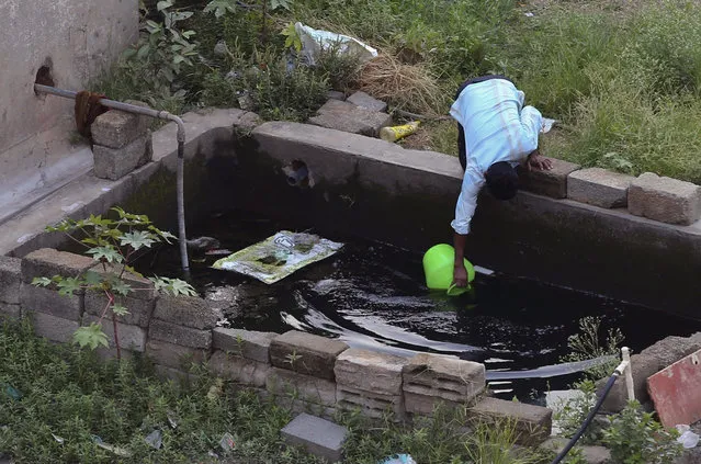 In this May 3, 2018 photo, a man fetches water from a concrete tank in an upcoming residential neighborhood in Bangalore, India. India’s Silicon Valley is bracing for yet another thirsty summer. Faucets are running dry and the lakes that once nurtured the southern city of Bangalore and its nearly 10 million residents are either parched or fetid with toxic effluents. Much like Cape Town in South Africa, Bangalore’s water woes have been in the making for some time with years of unplanned urbanization, rapid population growth and poor management of water resources. (Photo by Aijaz Rahi/AP Photo)