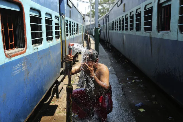 An Indian passenger bathes beside railway tracks on a hot summer afternoon in the outskirts of Jammu, India, Monday, May 28, 2018. The maximum temperature recorded in Jammu was 42.5 degrees Celsius, the highest this season which is a few degrees above normal for this time of the year. (Photo by Channi Anand/AP Photo)