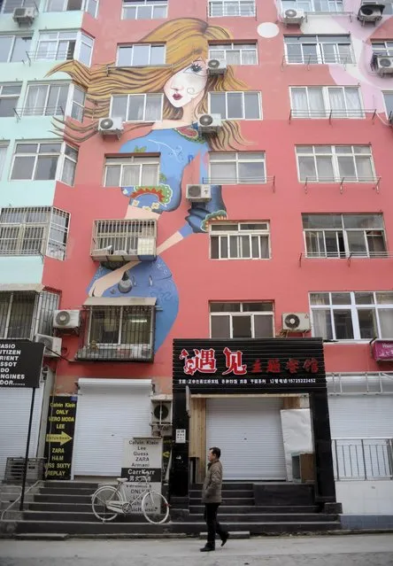 A man walks past a building with newly-painted murals along a pedestrian street in Qingdao, Shandong province, January 15, 2015. (Photo by Reuters/China Daily)