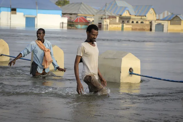 Men walk through floodwaters on a street in the town of Beledweyne, in Somalia Monday, May 15, 2023. Estimates from the UN Office for the Coordination of Humanitarian Affairs are that 460,000 people have been affected by flooding caused by heavy rains since mid-March. (Photo by AP Photo/Stringer)
