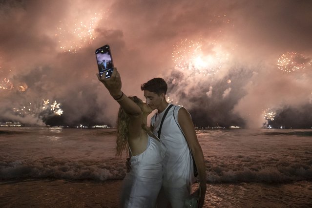 A couple kisses as fireworks light up the sky over Copacabana Beach during New Year's celebrations in Rio de Janeiro, Wednesday, January 1, 2025. (Photo by Bruna Prado/AP Photo)