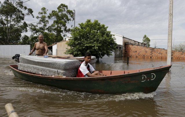 Paraguayans remove their belongings on a boat from their flooded houses near the Paraguay river in Asuncion, December 27, 2015. (Photo by Jorge Adorno/Reuters)