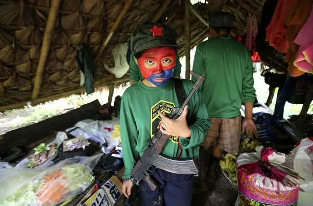 In this November 23, 2016 photo, a woman New People's Army guerrilla with face painted to conceal her identity holds her firearm inside a makeshift shelter at their rebel encampment tucked in the harsh wilderness of the Sierra Madre mountains, southeast of Manila, Philippines. Young Filipino rebels represent a new generation of Maoist fighters, who reflect the resiliency and constraints of an insurgency that has dragged on for nearly half a century through six Philippine presidencies. Crushing poverty, despair, government misrule and the abysmal inequality that has long plagued Philippine society were their best recruiter, according to the guerrillas. (Photo by Aaron Favila/AP Photo)