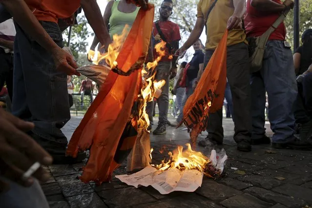 Supporters of Venezuela's President Nicolas Maduro burn a flag of the opposition party Popular Will (Voluntad Popular) close to the National Assembly in Caracas January 5, 2016. (Photo by Marco Bello/Reuters)
