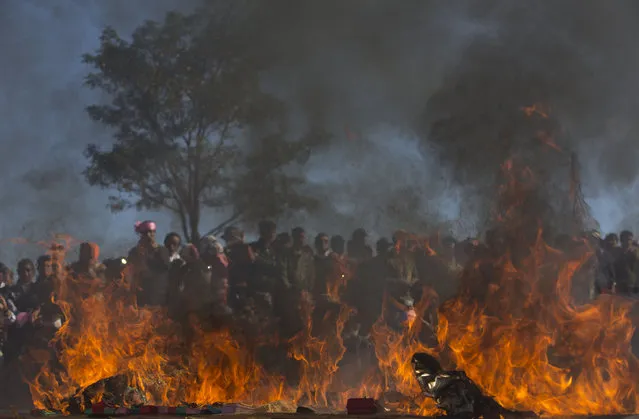 In this January 12, 2015 photo, Ta’ang people watch as opium, heroine and methamphetamine pills allegedly confiscated from pro-government militia are set on fire during a ceremony in Mar Wong Village, northern Shan state, Myanmar. (Photo by Gemunu Amarasinghe/AP Photo)