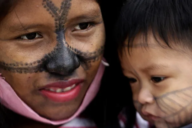 A Munduruku Indigenous woman and child from Alto Tapajos in the Brazilian state of Para attend a show of support for a government decree legalizing mining on Indigenous land outside the Supreme Court in Brasilia, Brazil, Monday, April 19, 2021. (Photo by Eraldo Peres/AP Photo)