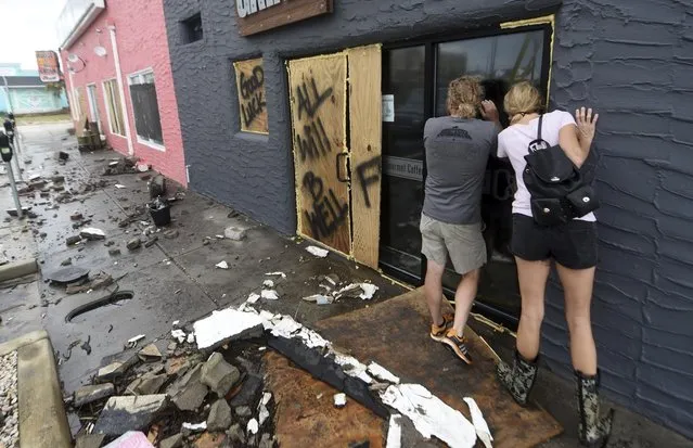 In this Monday, September 17, 2018 photo, Crush & Grind owners Brett Gurkin, left, and Nadine Antonelli look into their business along the Carolina Beach Boardwalk in Carolina Beach, N.C. The business sustained extensive damage due to Hurricane Florence. (Photo by Matt Born/The Star-News via AP Photo)