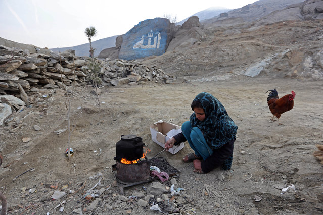 Firoza, a 12-yea-old Afghan girl, makes tea outside her home on the outskirts of Kabul, Afghanistan, Thursday, February 5, 2015. Arabic word Allah, or God, is painted on a rock in the background. (Photo by Rahmat Gul/AP Photo)