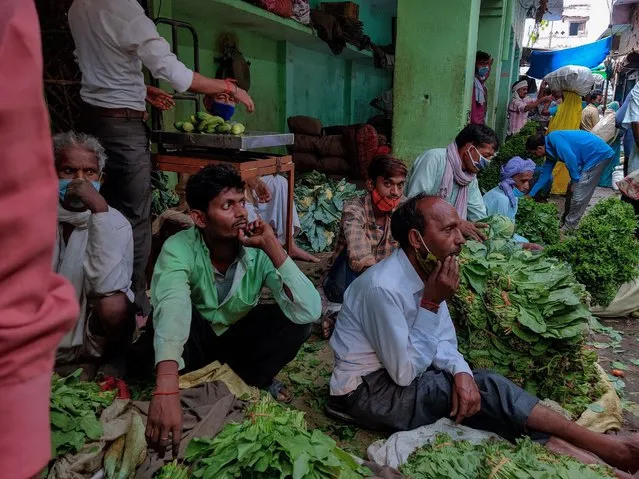 In this May 13, 2021 file photo, people sit at a vegetables market in Prayagraj, Uttar Pradesh, India. A dip in the number of coronavirus cases in Mumbai is offering a glimmer of hope for India, which is suffering through a surge of infections. (Photo by Rajesh Kumar Singh/AP Photo)
