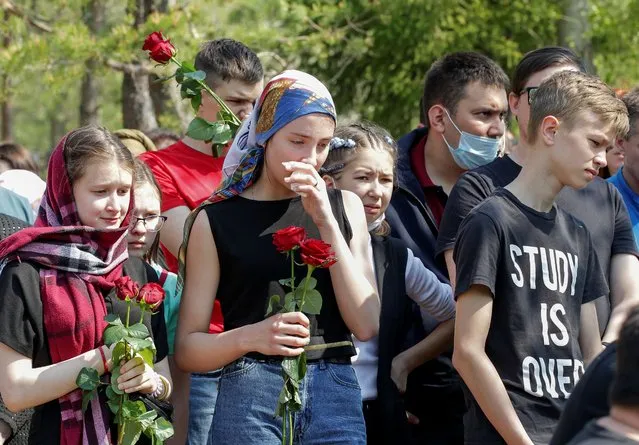 Mourners stand near the grave of Elvira Ignatieva, an English language teacher killed in the massacre at School Number 175, during a funeral at a cemetery in Kazan, Russia on May 12, 2021. (Photo by Alexey Nasyrov/Reuters)