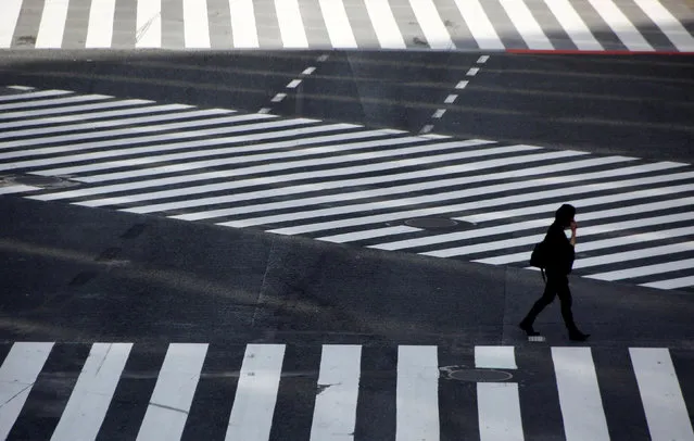 A pedestrian walks at a scramble crossing at Shibuya shopping district, the so-called Shibuya crossing, in Tokyo, Japan, October 10, 2018. (Photo by Kim Kyung-Hoon/Reuters)
